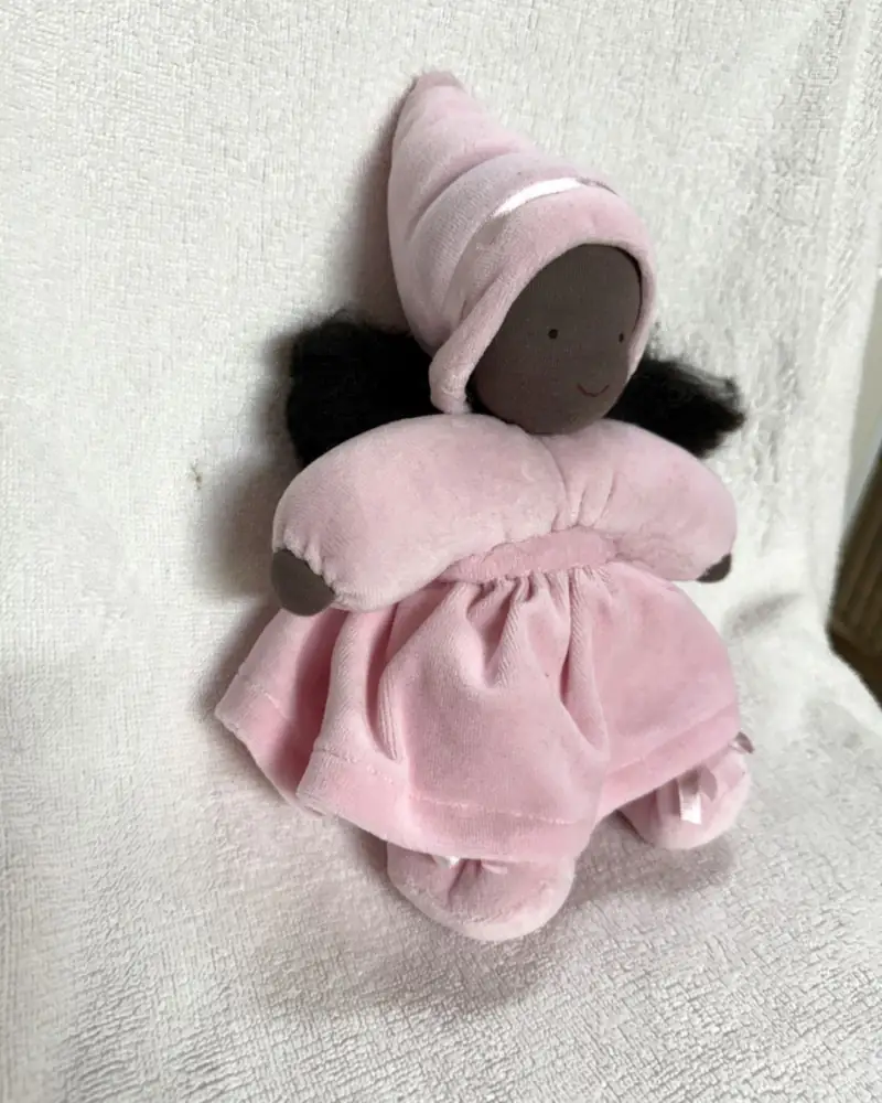Fadinha de gorro rosa vista em ângulo, com fita rosa no gorro e vestido aveludado franzido na cintura