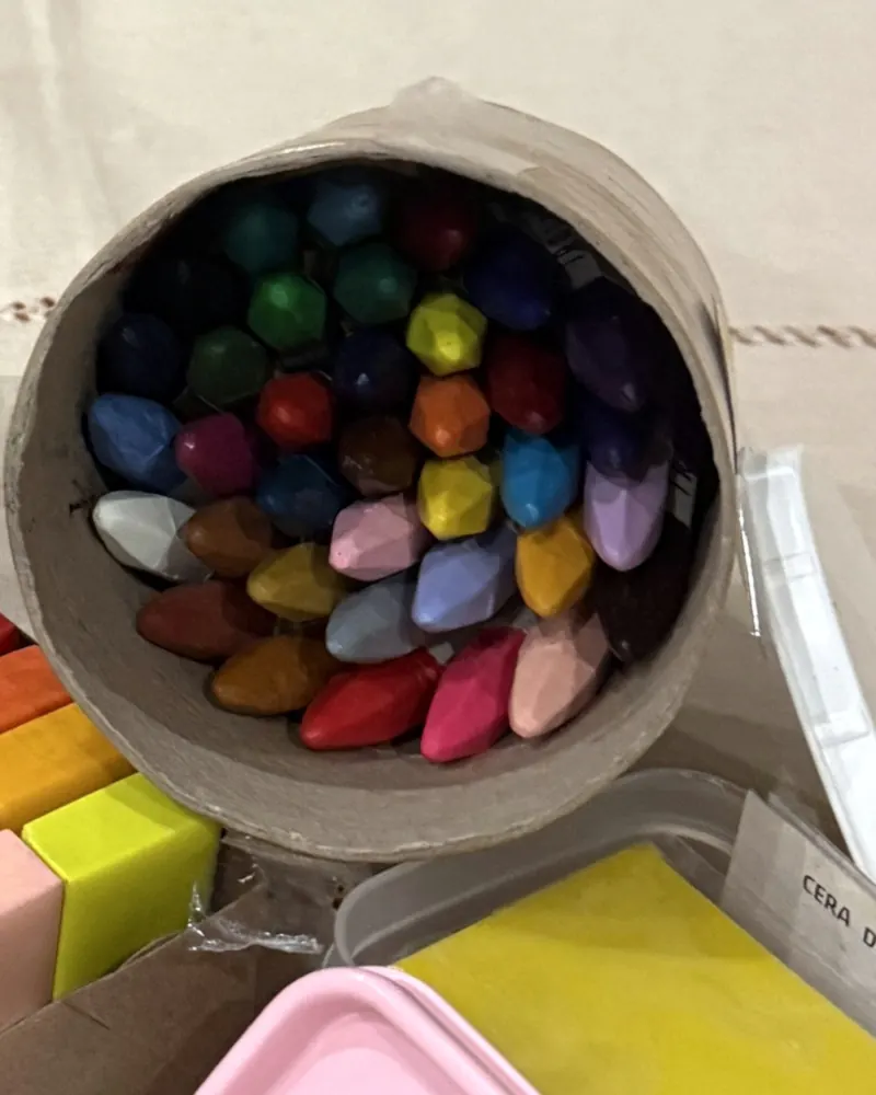 Bastões de giz de cera de abelha vistos de cima dentro do tubo kraft, em azul, verde, vermelho, rosa, amarelo e lilás