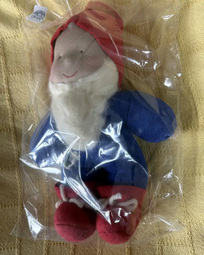 Gnomo Maroto visto de perto no saquinho, com bochechas rosadas, gorro vermelho e botinhas amarradas com cordão