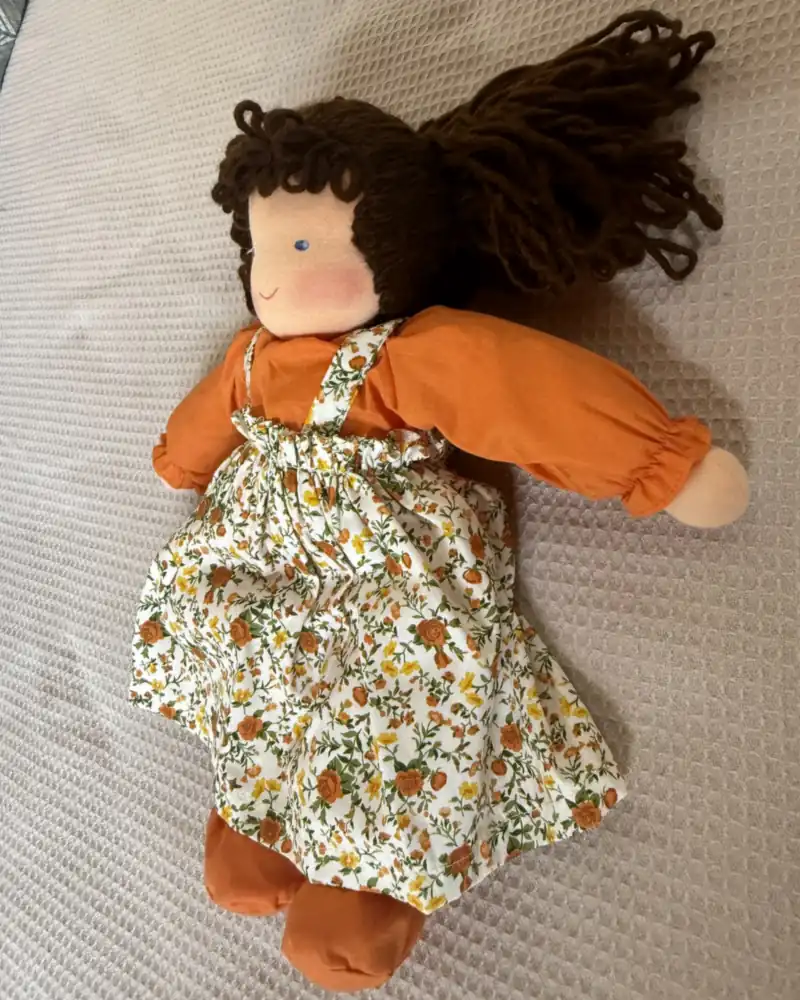 Mara Morena de lado, com os cachos espalhados e as mangas franzidas da blusa laranja