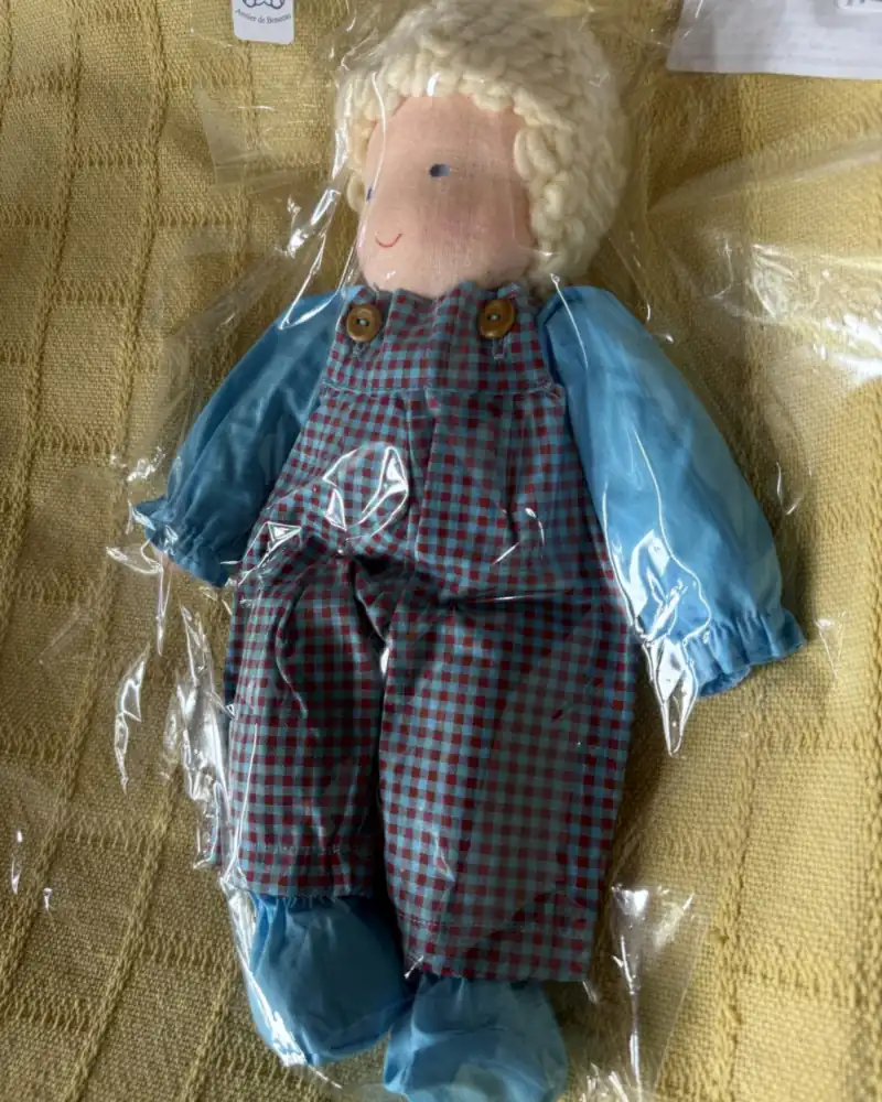 Menino Travesso no saquinho, visto um pouco de lado, com os sapatinhos azuis